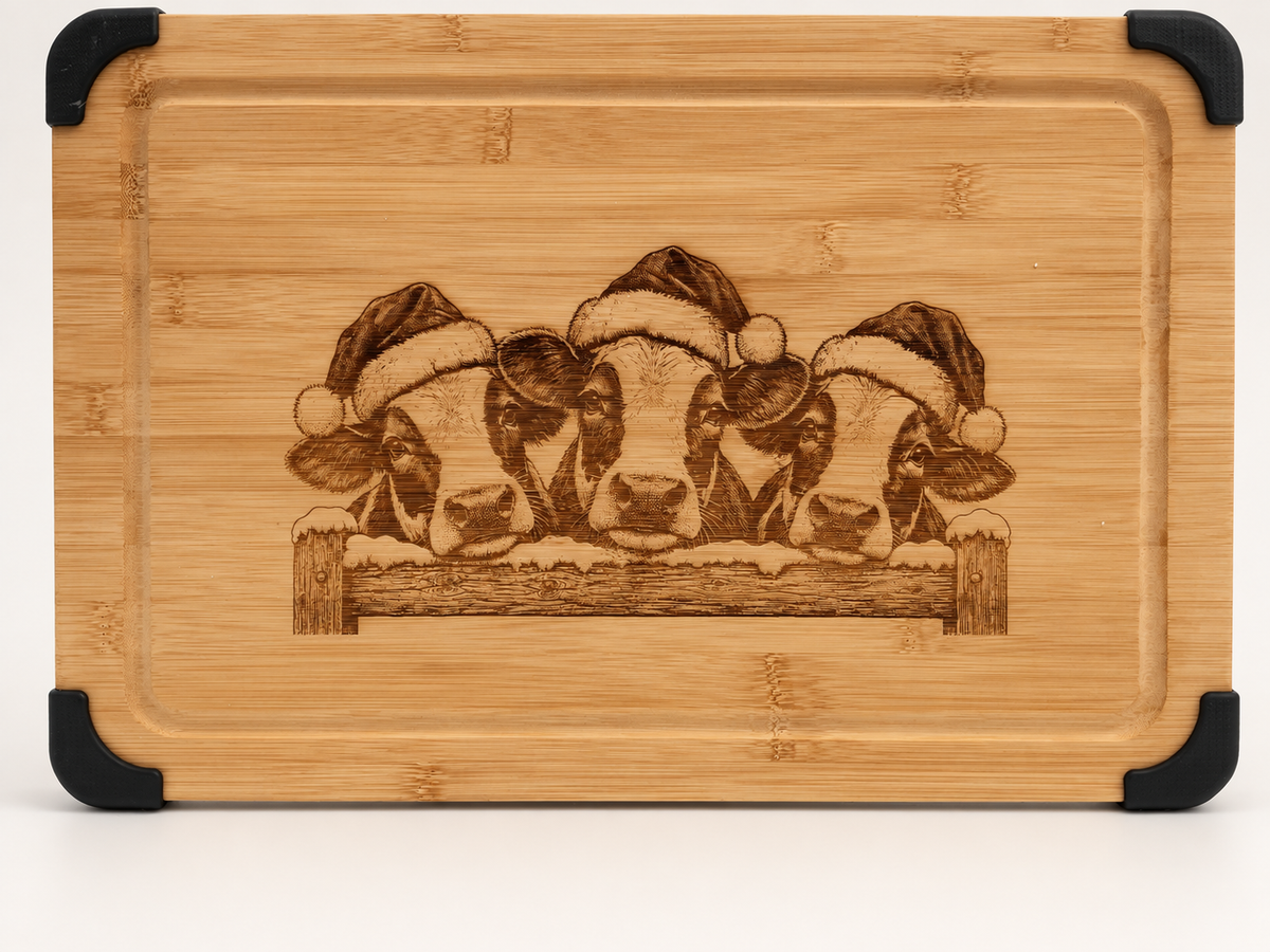 Christmas cows engraved bamboo serving board with Santa hats, snowy fence, juice groove and black corner grips.
