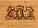 Close-up of Christmas horses engraved on warm honey-toned bamboo with natural grain visible.