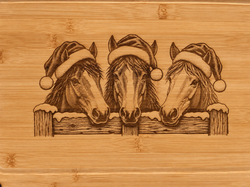 Close-up of Christmas horses engraved on warm honey-toned bamboo with natural grain visible.