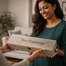 Woman receiving a wooden box with 'New Beginnings' engraving in a home setting.