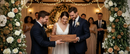 Wedding couple receiving a personalized live-edge engraved board at a warmly lit reception with guests in the background.